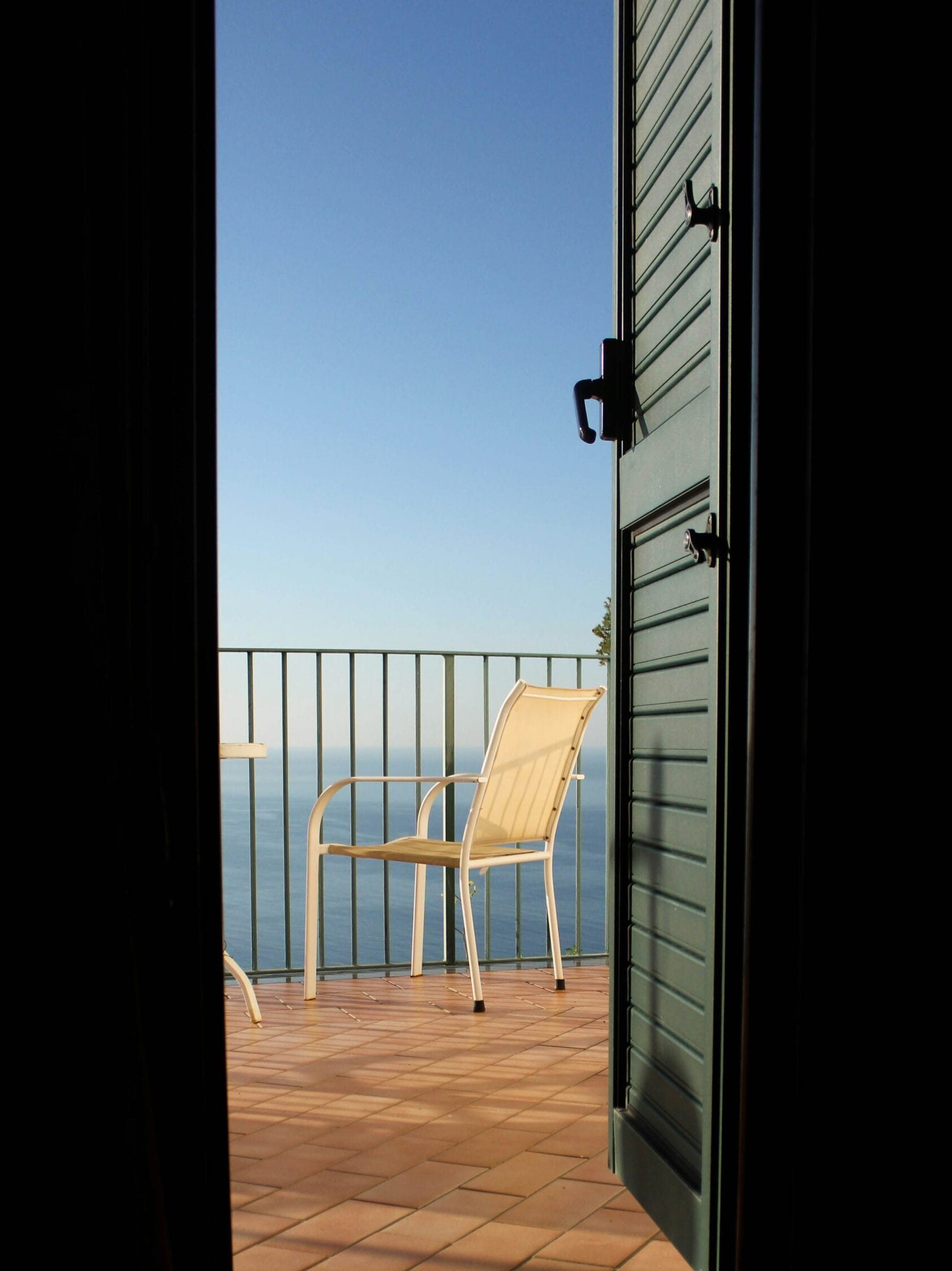 Vue depuis l'intérieur vers terrasse avec chaise face à la mer. Invitation à s'inscrire Atypik Home