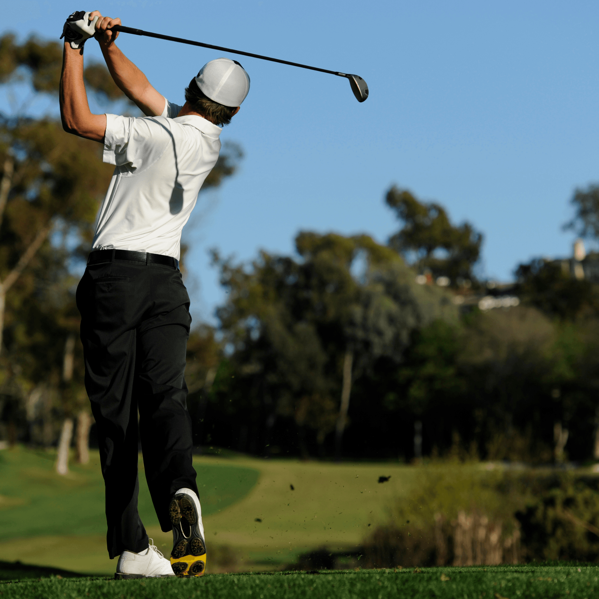 Un golfeur en plein swing sur un parcours verdoyant sous un ciel bleu. Hobbit's Home, témoignage client hébergement insolite