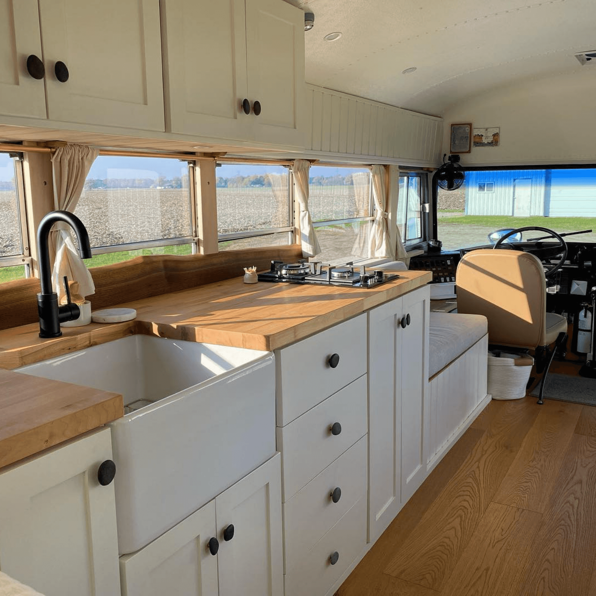 Cuisine fonctionnelle avec plan de travail en bois, évier et plaques de cuisson dans bus aménagé
