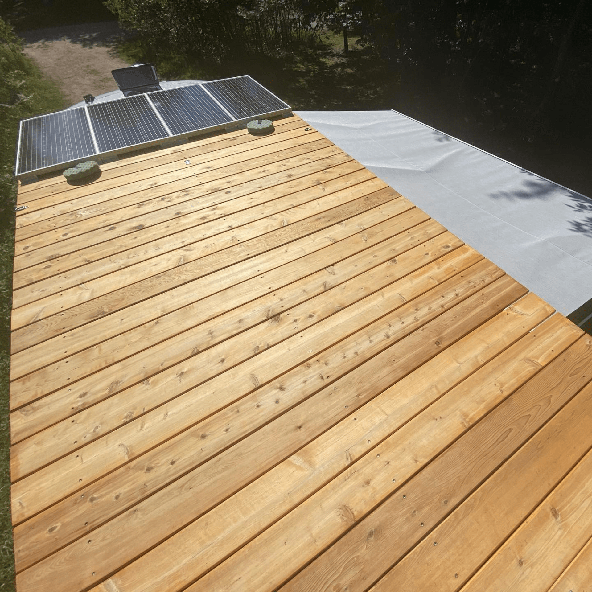 Terrasse en bois sur le toit du love bus avec panneaux solaires, hébergement écologique