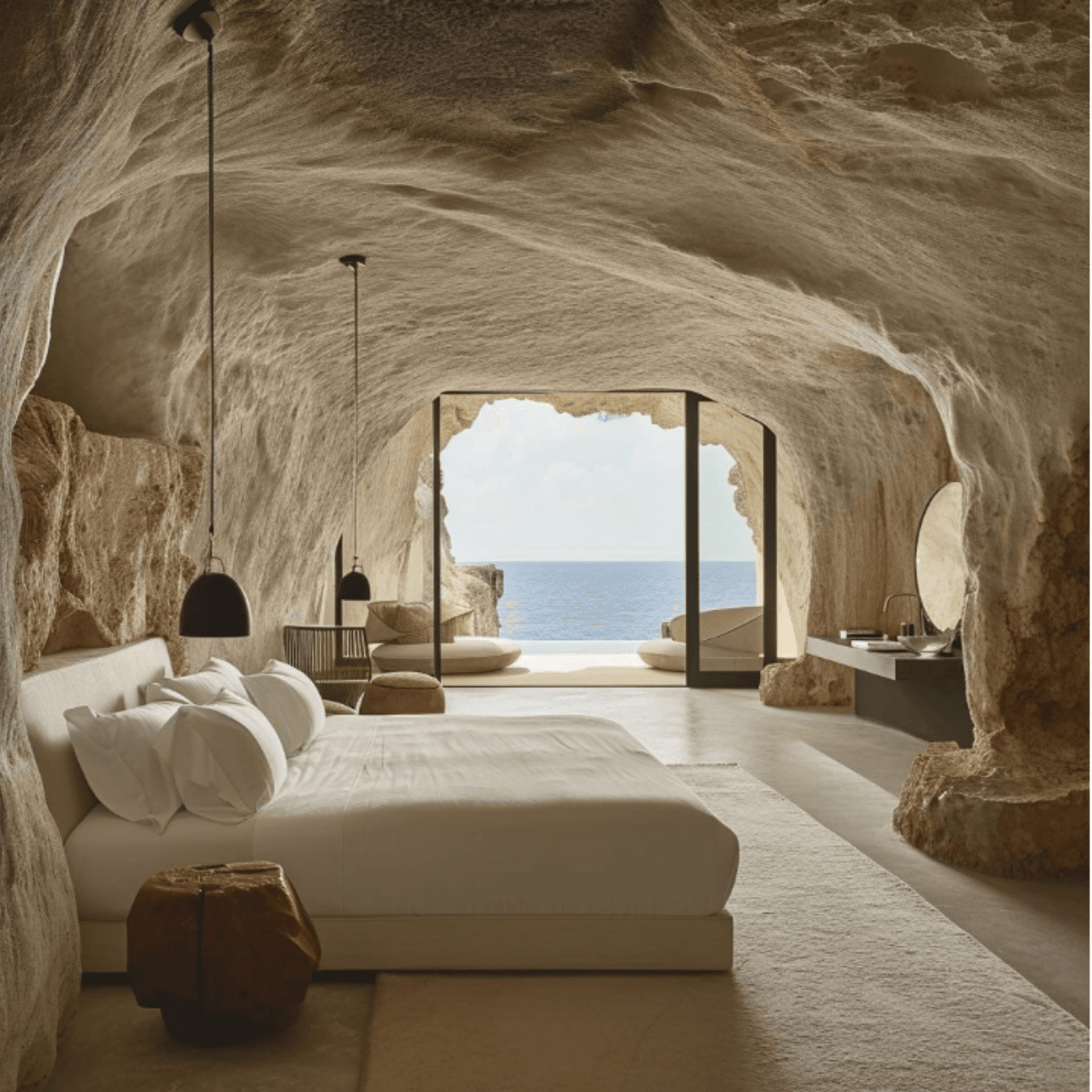 Chambre villa troglodyte avec lit face à l'océan et colonnes antiques