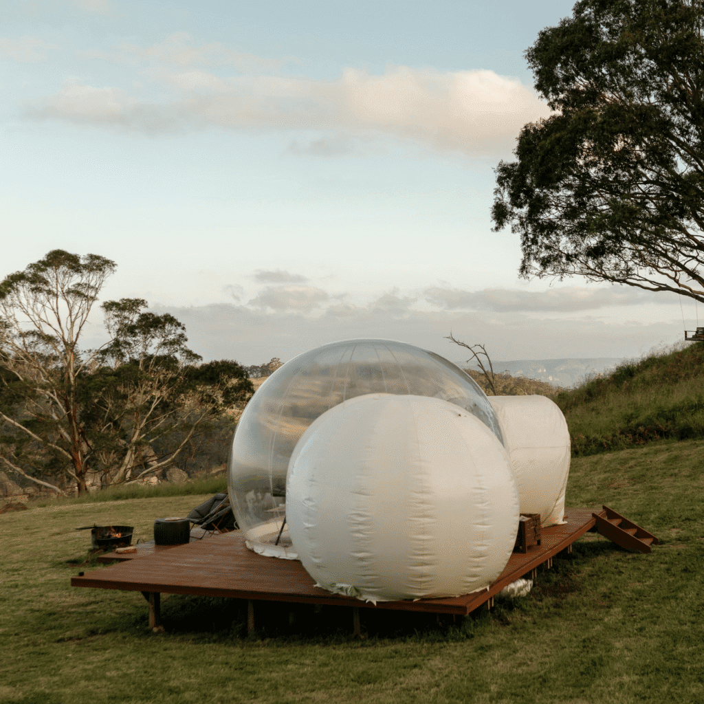 Réservation bulle transparente sous un ciel nuageux, expérience immersive en pleine nature.