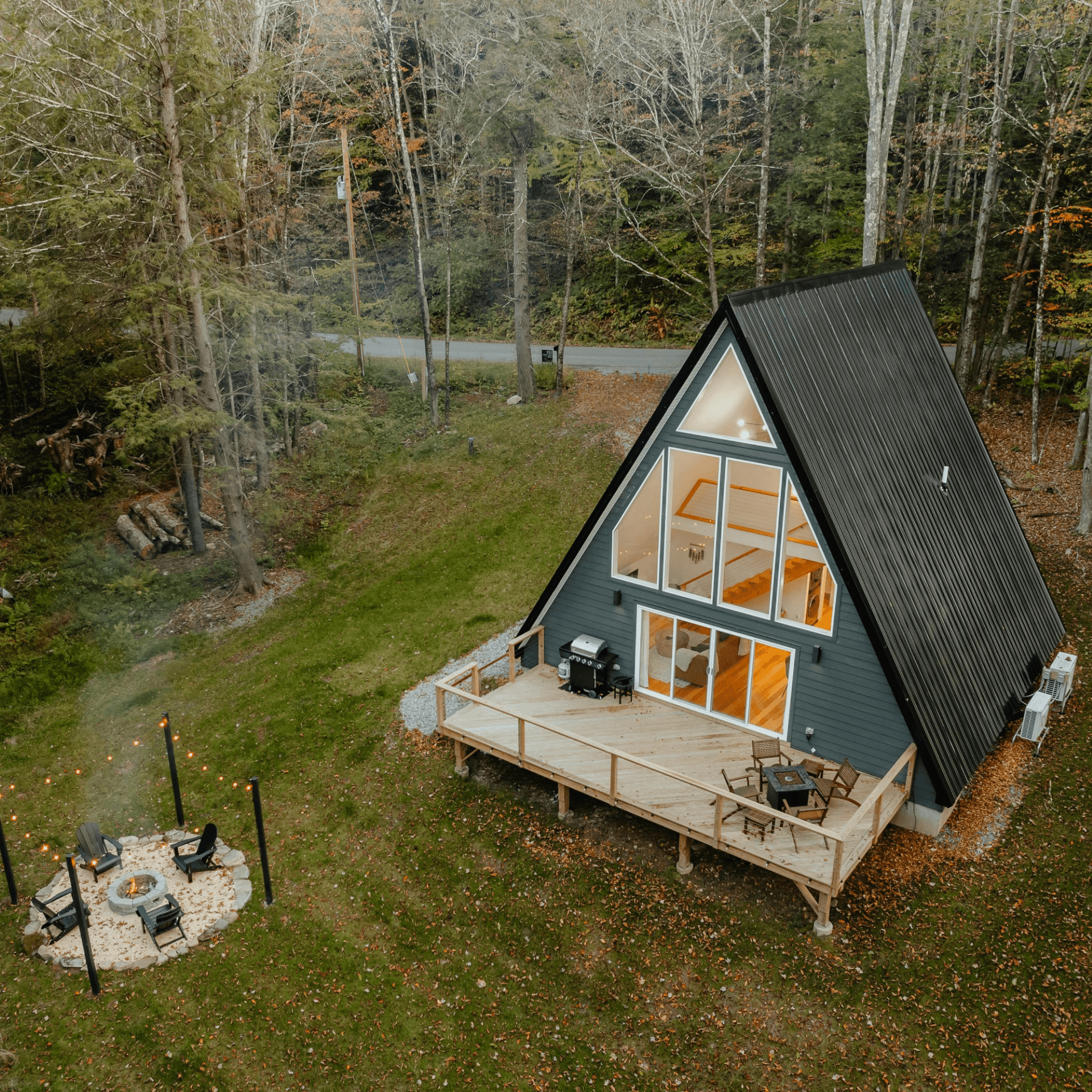 Vue drone cabane triangulaire noire forêt automne terrasse bois espace feu