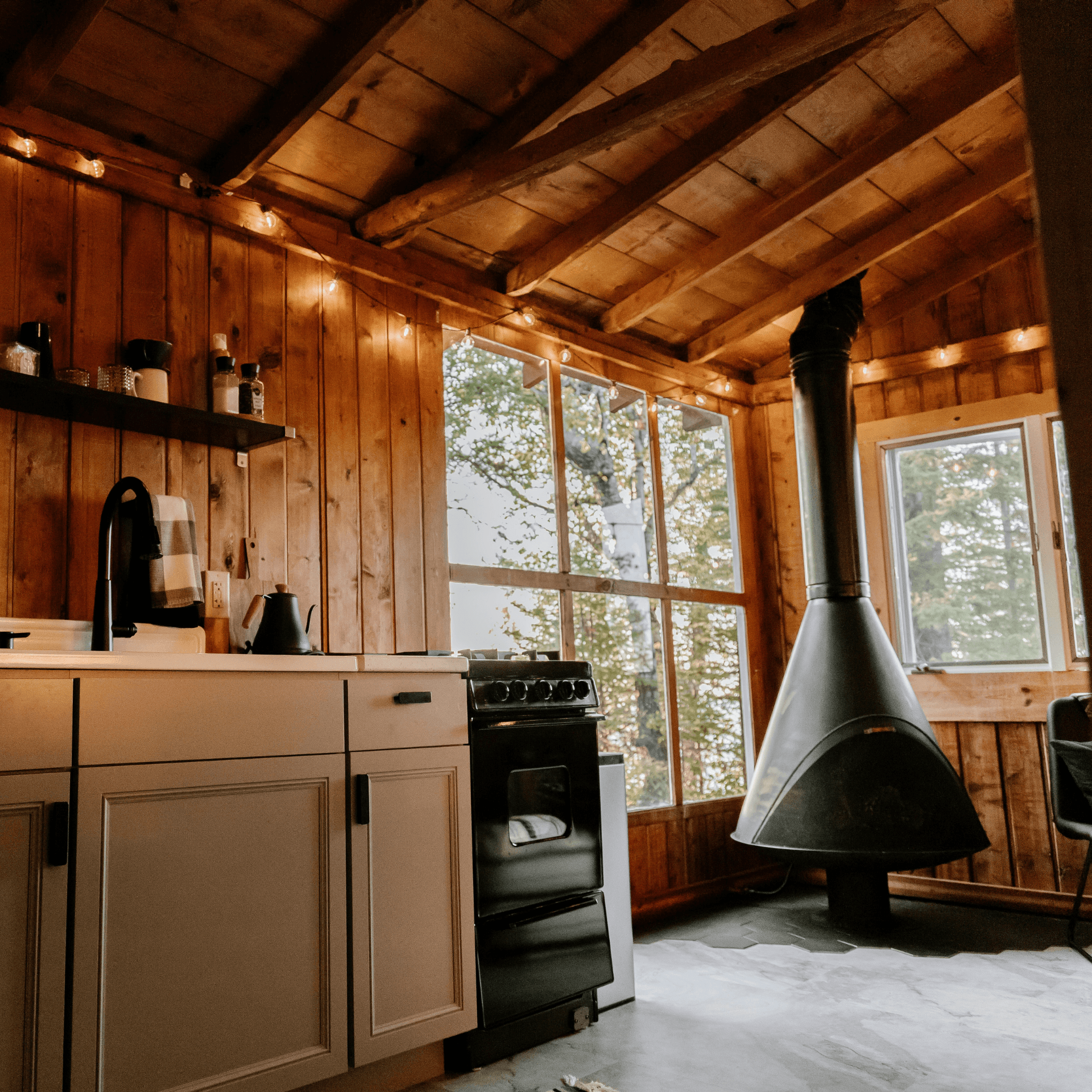 Cuisine bois rustique poêle noir suspendu plafond poutres apparentes fenêtres lumineuses