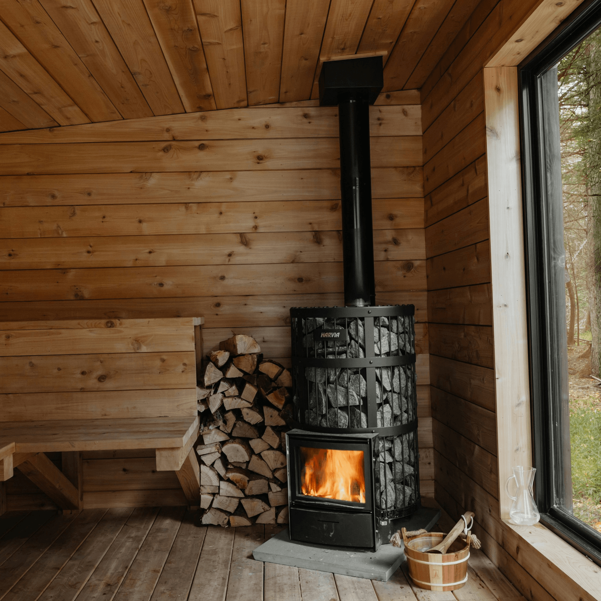Poêle sauna noir cylindrique bois empilé intérieur cabane bois naturel